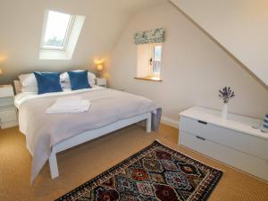 a bedroom with a bed with blue pillows and a rug at Rose Cottage in Hereford