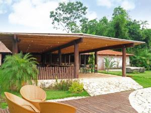 a wooden pavilion with chairs and tables in a yard at Muiraquitã Hotel in Ourilândia do Norte