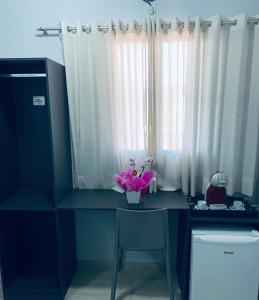 una stanza con una scrivania con un vaso di fiori sopra di Santo Antônio Hotel Ltda ad Angatuba