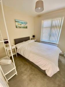 a bedroom with a white bed and a window at Eden Stay in Morecambe