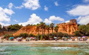 a beach with umbrellas and people on the beach at apartamento preciosas vistas campoamor in Dehesa de Campoamor