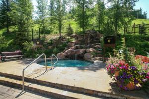 a small pool with a waterfall in a garden at Village Hall 1415 by East West Hospitality in Beaver Creek