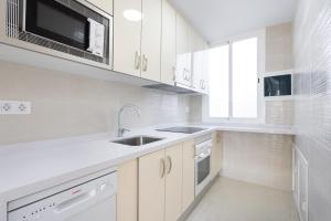 a white kitchen with a sink and a microwave at Two apartments 250m from las americas Beach in Playa de las Americas