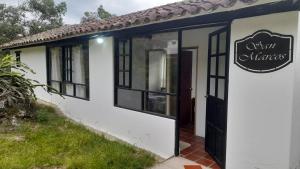 a small white building with a black door at San Marcos in Villa de Leyva