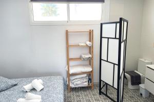 a room with a bed and a shelf with towels at Agoodplan Aitana Playa El Palmar in El Palmar