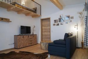 a living room with a blue chair and a television at Loftwohnung Kaiserblick im Inntal - 83 qm - zentral & ruhig in Flintsbach am Inn