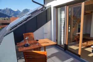 a balcony with a wooden table and chairs on a roof at Loftwohnung Kaiserblick im Inntal - 83 qm - zentral & ruhig in Flintsbach am Inn