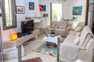 a living room with a couch and a tv at Beachfront Luxury Villa Letizia - Sea View Terraces & Green Solar Energy in Quartu SantʼElena