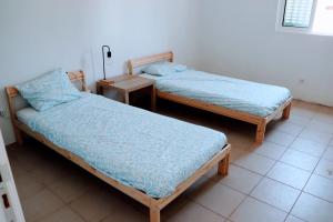 two twin beds in a room with a table at Casa do Trevo in Foros do Locário