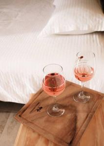 two glasses of wine on a wooden tray next to a bed at Hotel EL Porvenir in Tunas Blancas