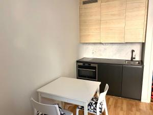 een kleine keuken met een witte tafel en stoelen bij Simply chic Kamppi FI in Helsinki
