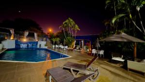 Una piscina de noche con sillas y sombrilla. en Hotel Portinari Centro, en Foz do Iguaçu