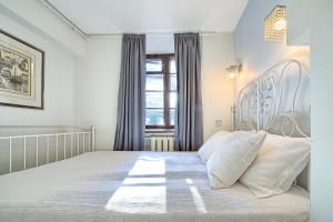 a bedroom with a large white bed with a large window at Elegant apartment in Old town Vilnius SELF CHECK IN 24x7 by H&H in Vilnius