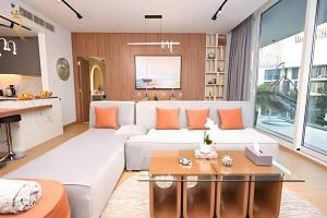 a living room with a white couch and orange pillows at Seaside 1BR Retreat in Saadiyat Island - Pool, Gym & Near Saadiyat Beach & Louvre Abu Dhabi in Abu Dhabi