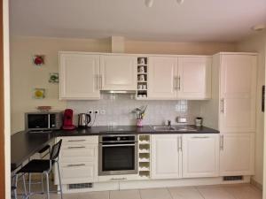 a white kitchen with white cabinets and a sink at duplex en maison individuelle de 70 m2avec jardin in Viry-Châtillon