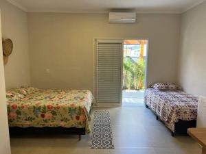 1 Schlafzimmer mit 2 Betten und einer Glasschiebetür in der Unterkunft Casa Mero no Residencial Mar Verde em Caraguatatuba in Caraguatatuba + 26 Fotos