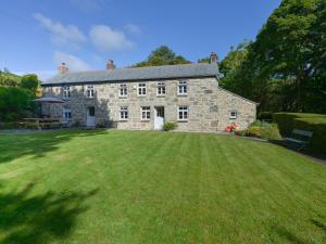 een groot stenen huis met een grote grastuin bij Heather Cottage in Penzance