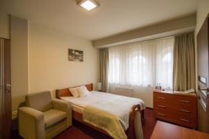 ラチブシュにあるZajazd Biskupiのベッドルーム1室(ベッド1台、椅子、窓付)