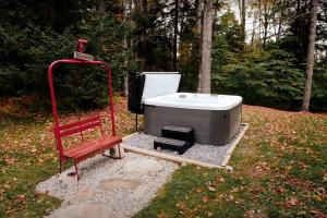 a hot tub and a red bench in the grass at Green Mountain base camp for year-round adventure! in Londonderry