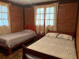 a bedroom with two beds and a brick wall at Cabaña la Escondida in Cruz de Madroño