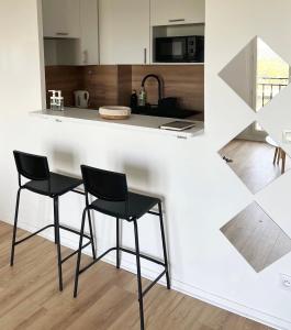 a kitchen with two black chairs at a counter at COSY NOISY Charmant 2 pièces entre Paris et DisneyLand in Noisy-le-Grand