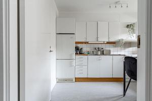 a white kitchen with white cabinets and a black chair at Budget-friendly studio on Södermalm, construction work in Stockholm