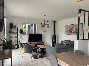 un salon avec un canapé et une télévision dans l'établissement Villa Kerleven- 150m plage - Spa intérieur-piscine, à La Forêt-Fouesnant