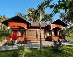 a house with a palm tree in front of it at Betel Brooks Resort in Maraiyūr