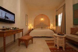 Un dormitorio con una cama, un televisor y un sofá. en Dar Saida Beya, en Tozeur