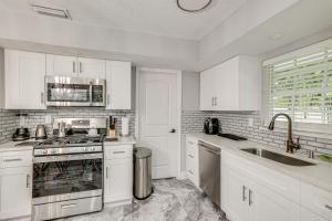 a white kitchen with a stove and a sink at Pet-Friendly Gem with Pool and Yard in West Palm Beach in West Palm Beach