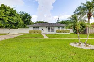 a white house with palm trees in a yard at Pet-Friendly Gem with Pool and Yard in West Palm Beach in West Palm Beach