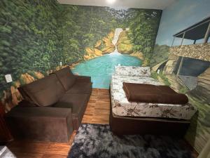 ein Zimmer mit einem Sofa und einem Wandgemälde eines Flusses in der Unterkunft Casa Do Guh in São Thomé das Letras