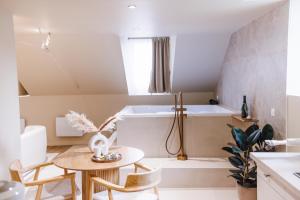 La salle de bains est pourvue d'une baignoire, d'une table et de chaises. dans l'établissement Eden Room - Luxe, Balnéo & Sauna, au Mans
