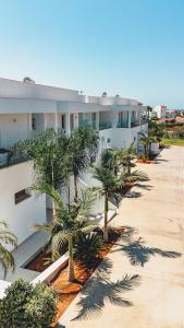 a row of palm trees in front of a building at Grand White Apartments in Agios Ioannis