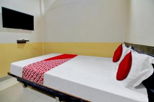 a bedroom with a bed with red pillows and a tv at Hotel O Vinit Lodging in Nagpur