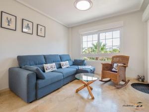 a living room with a blue couch and a glass table at CASA DE FLAMENCO in Orihuela Costa