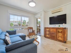 a living room with a blue couch and a flat screen tv at CASA DE FLAMENCO in Orihuela Costa