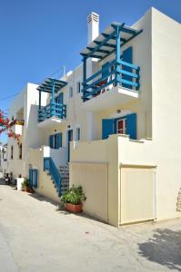 a white building with blue balconies on a street at Studios Kahlua in Agios Prokopios