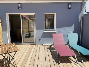 two chairs and a table on a wooden deck at Wissant Maison Chez Jeanne in Wissant