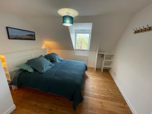 a bedroom with a bed with blue pillows and a window at Wissant Maison Chez Jeanne in Wissant +11 photos