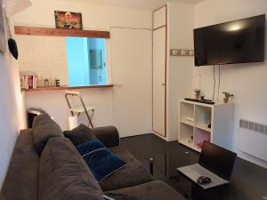 a living room with a couch and a laptop on a table at Studio dans résidence avec piscine à 50m de la mer in Roquebrune-Cap-Martin +5 photos
