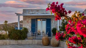 a house with a blue door and some flowers at Themonia Studios Kimolos in Kimolos