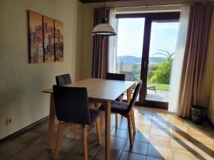 a dining room table with chairs and a large window at Komfort-Ferienwohnung Auf der Eulenburg in Grafengehaig