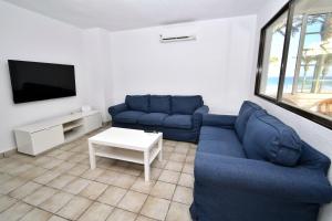 a living room with blue couches and a tv at Muchavista Playa Alicante in El Campello