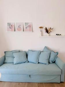 a blue couch in a living room with three pictures on the wall at Maison Comì in Frattamaggiore +27 photos