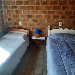 una camera da letto con due letti e un muro di mattoni di Casa 2 dormitorios B a Villa Guntz Altre 4 foto