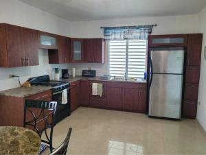 une cuisine avec des armoires en bois et un réfrigérateur en acier inoxydable dans l'établissement Rincon Familiar, à Arecibo