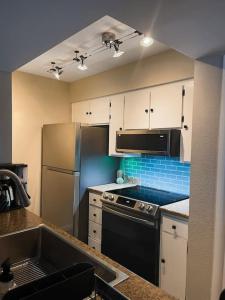 a kitchen with white cabinets and a black refrigerator at Cheerful & Relaxing 5 Location Pool Parking in Tucson
