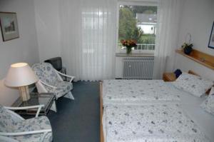 1 dormitorio con 2 camas, sillas y ventana en Hotel Ebnet Garni, en Lindau