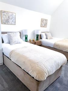 two beds in a bedroom with white walls at The Luxe Haven Penthouse - Sleeps 4 Apartment Nottingham City Centre in Nottingham